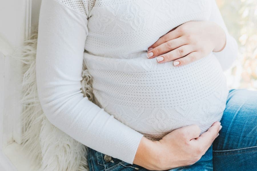 Mujer embarazada sosteniéndose suavemente la panza