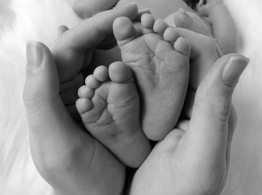 Manos sosteniendo con ternura los pies de un recién nacido